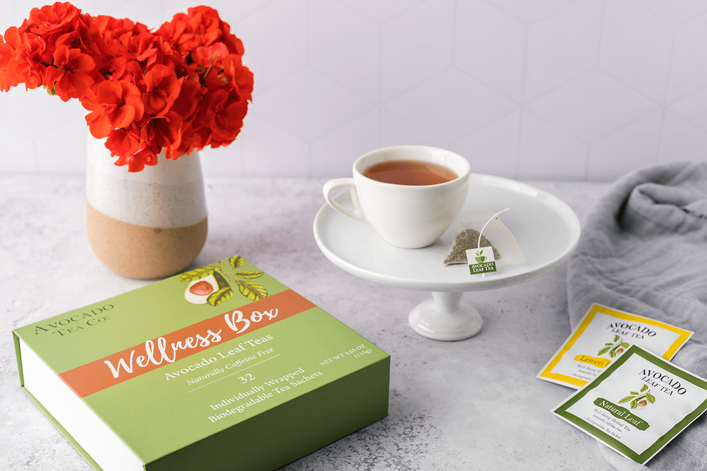 A wellness box of 32 individually wrapped tea sachets, a cup of hot tea, single serve lemon tea, a single serve natural tea
