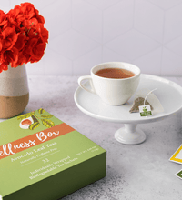 A wellness box of 32 individually wrapped tea sachets, a cup of hot tea, single serve lemon tea, a single serve natural tea